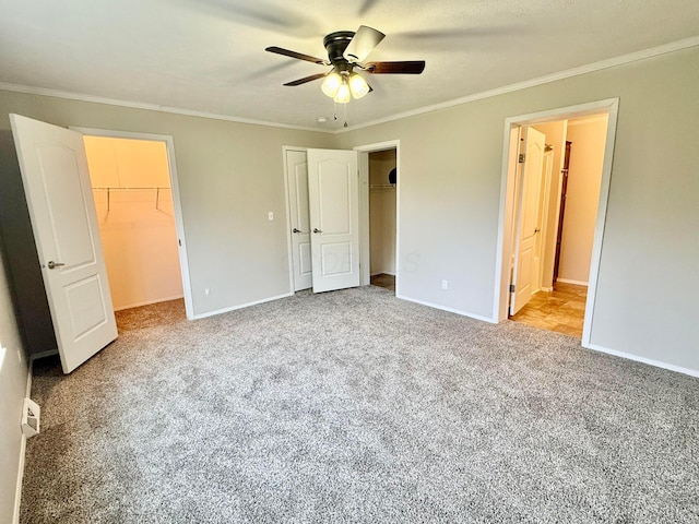 unfurnished bedroom with light carpet, a walk in closet, ceiling fan, ornamental molding, and a closet