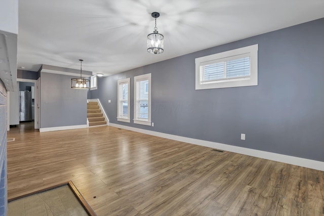 unfurnished living room with hardwood / wood-style flooring and a notable chandelier