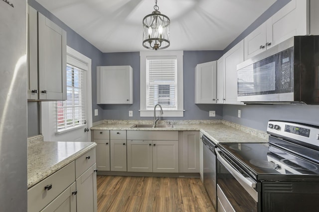 kitchen featuring dark hardwood / wood-style flooring, stainless steel appliances, sink, pendant lighting, and a chandelier