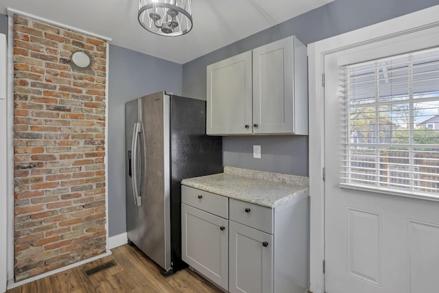 kitchen featuring light stone countertops, stainless steel fridge with ice dispenser, light wood-type flooring, and an inviting chandelier