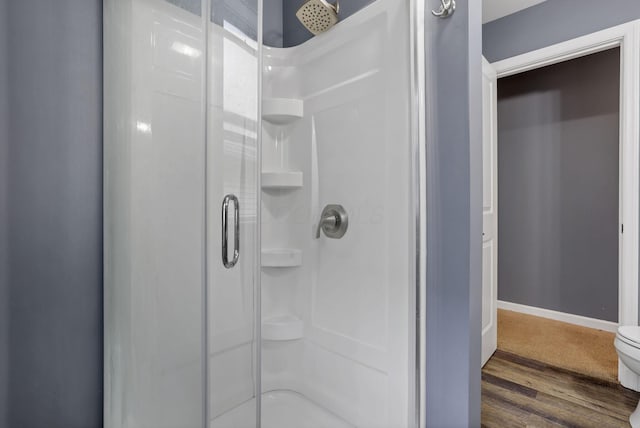 bathroom featuring hardwood / wood-style floors, toilet, and a shower with door