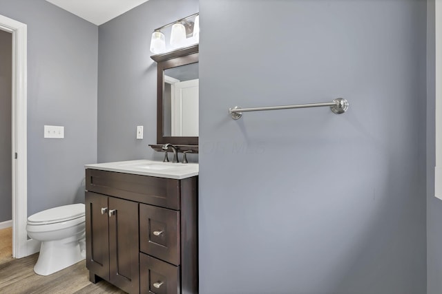 bathroom with hardwood / wood-style floors, vanity, and toilet