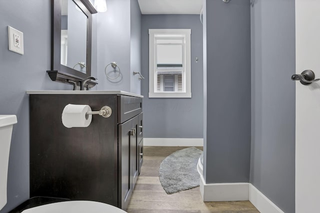 bathroom with hardwood / wood-style floors, vanity, and toilet