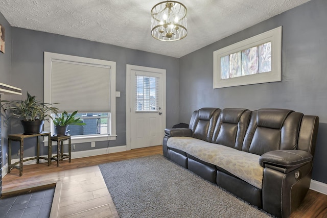 living room featuring hardwood / wood-style flooring, a notable chandelier, and a textured ceiling