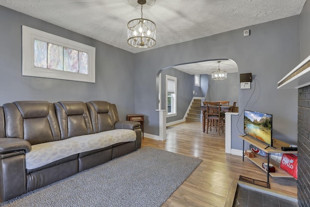 living room featuring a notable chandelier, wood-type flooring, and a textured ceiling