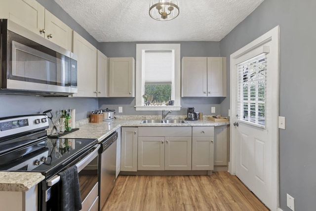 kitchen featuring a textured ceiling, stainless steel appliances, light hardwood / wood-style flooring, and sink