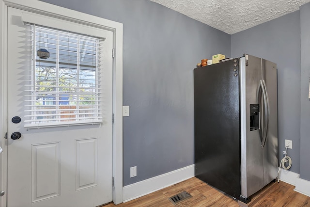 kitchen featuring stainless steel fridge with ice dispenser, a textured ceiling, and hardwood / wood-style flooring