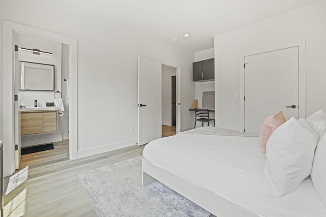 bedroom featuring ensuite bath and light wood-type flooring