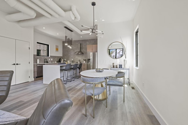 dining room featuring sink, a chandelier, and light wood-type flooring