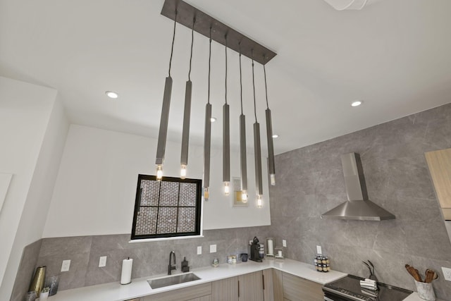 kitchen with decorative backsplash, decorative light fixtures, wall chimney exhaust hood, and sink