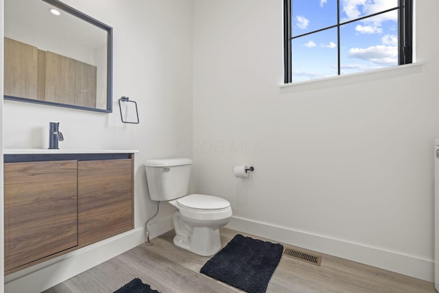 bathroom with hardwood / wood-style floors, vanity, and toilet