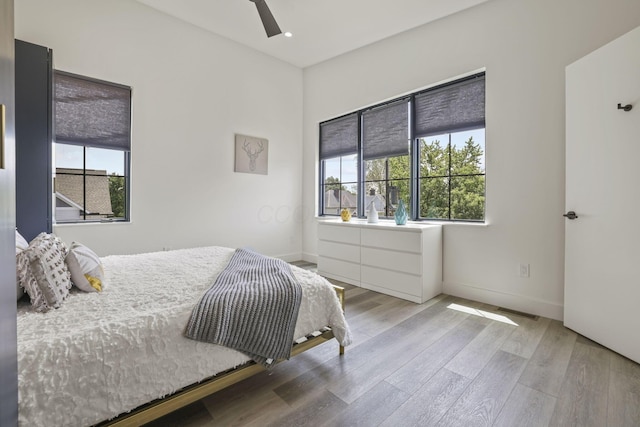 bedroom featuring hardwood / wood-style flooring, ceiling fan, and multiple windows