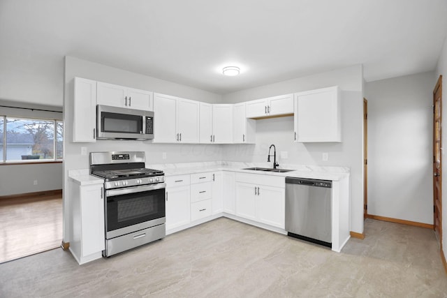 kitchen with white cabinetry, sink, light stone counters, and appliances with stainless steel finishes