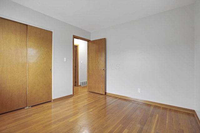 unfurnished bedroom with light wood-type flooring and a closet