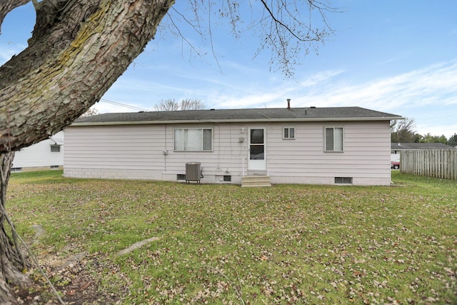 rear view of property with central air condition unit and a lawn