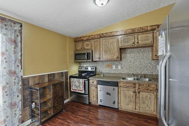 kitchen with sink, dark wood-type flooring, a textured ceiling, lofted ceiling, and appliances with stainless steel finishes