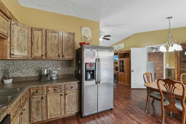 kitchen with dark hardwood / wood-style flooring, backsplash, lofted ceiling, ceiling fan with notable chandelier, and appliances with stainless steel finishes