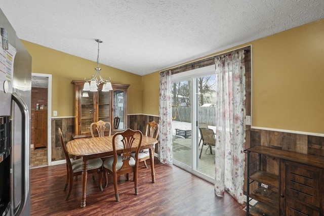 dining room featuring lofted ceiling, a textured ceiling, dark wood-type flooring, and a notable chandelier