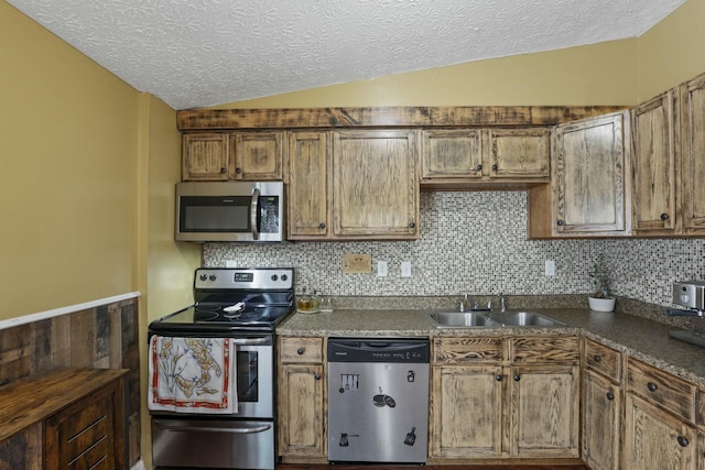 kitchen with appliances with stainless steel finishes, tasteful backsplash, a textured ceiling, sink, and lofted ceiling