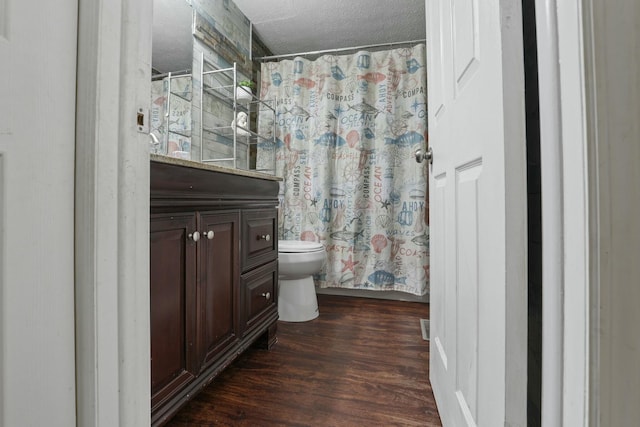 full bathroom with hardwood / wood-style floors, vanity, toilet, a textured ceiling, and shower / bath combo with shower curtain