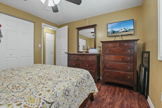 bedroom with a textured ceiling, ceiling fan, dark wood-type flooring, and a closet