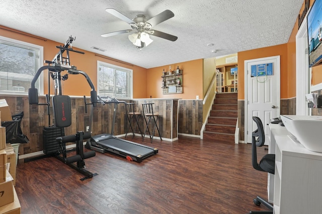 workout area featuring dark hardwood / wood-style floors, ceiling fan, and wooden walls