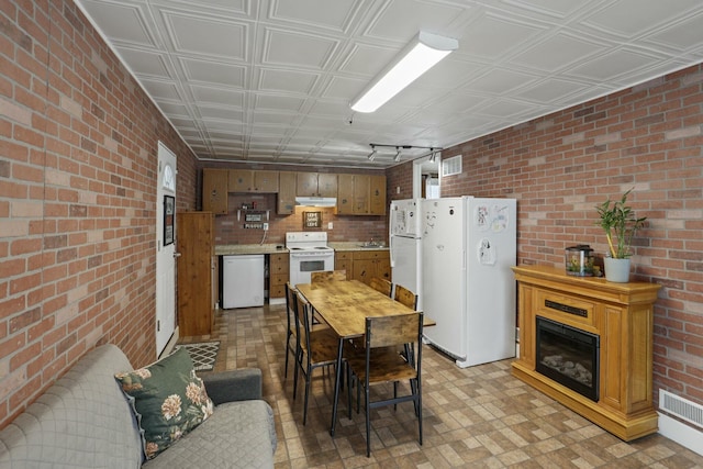 kitchen featuring brick wall and white appliances