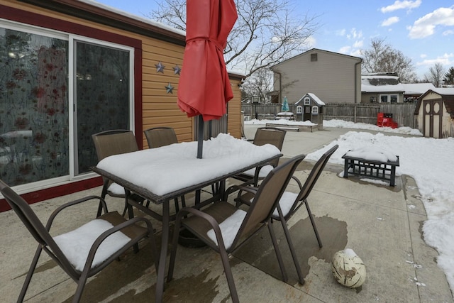 snow covered patio featuring a shed