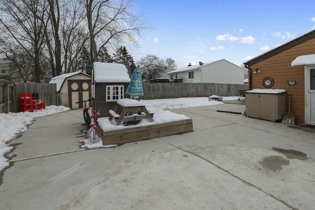 snow covered patio featuring a shed