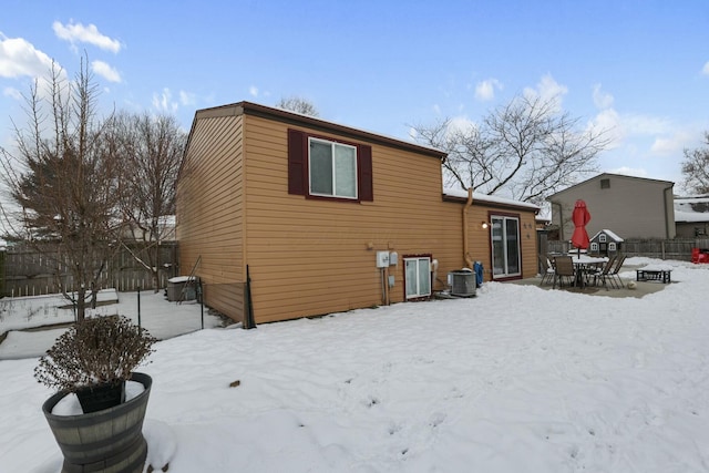 snow covered house featuring cooling unit