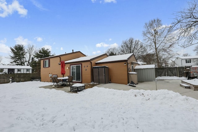 snow covered rear of property featuring a shed