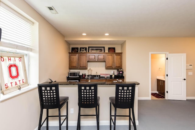 7201 Dean Farm Rd, New Albany, OH 43054 - kitchen featuring stainless steel microwave, a breakfast bar area, brown cabinets, recessed lighting, and baseboards