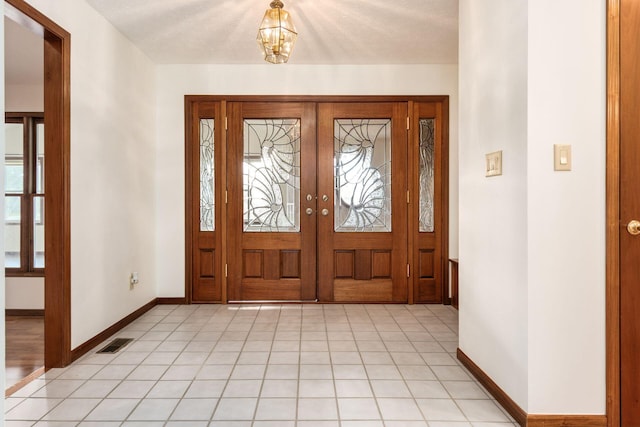 entryway with a chandelier, a textured ceiling, and french doors