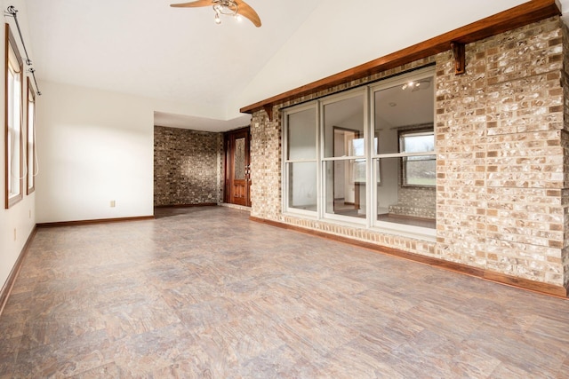 empty room featuring ceiling fan, brick wall, and lofted ceiling