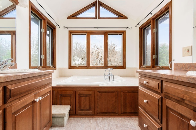 bathroom with a washtub, vanity, and vaulted ceiling