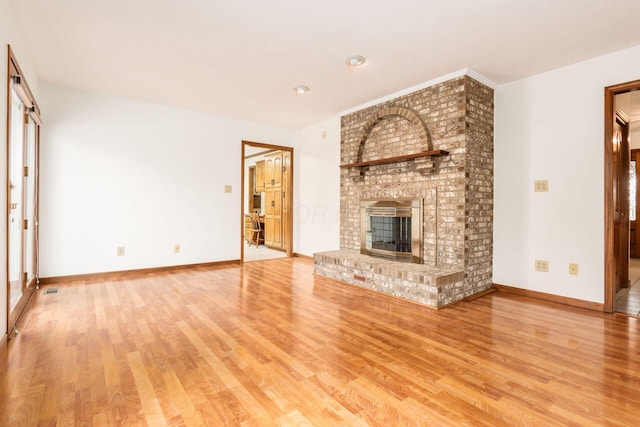 unfurnished living room featuring light wood-type flooring and a brick fireplace