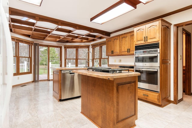 kitchen featuring stainless steel appliances, a kitchen island, coffered ceiling, and crown molding