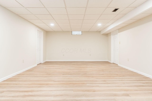 basement with a paneled ceiling and light wood-type flooring