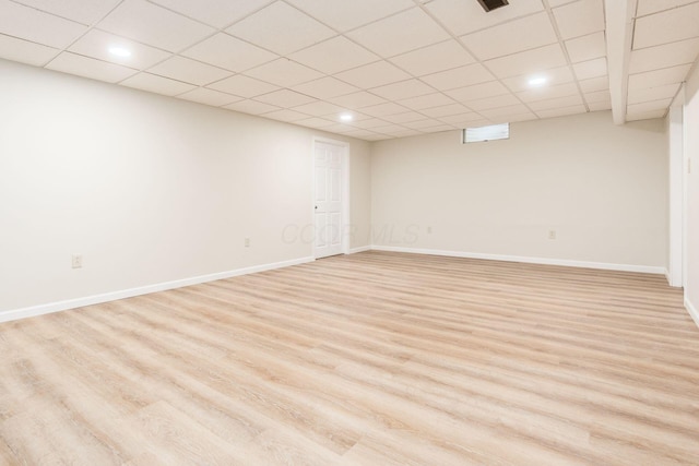 basement featuring a paneled ceiling and light hardwood / wood-style flooring