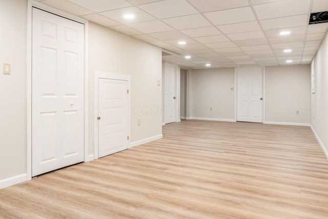 basement featuring a paneled ceiling and light hardwood / wood-style floors