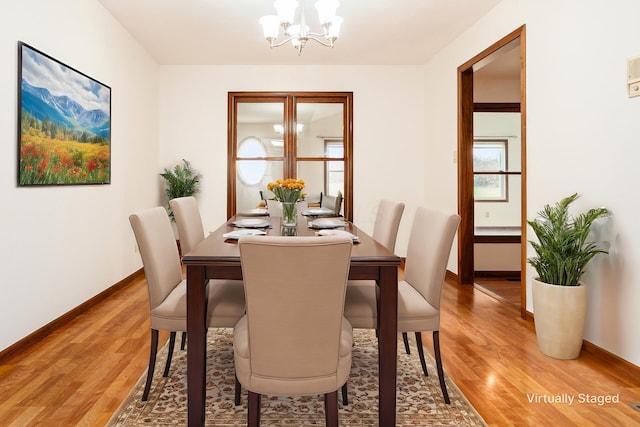 dining space with light hardwood / wood-style flooring and a notable chandelier