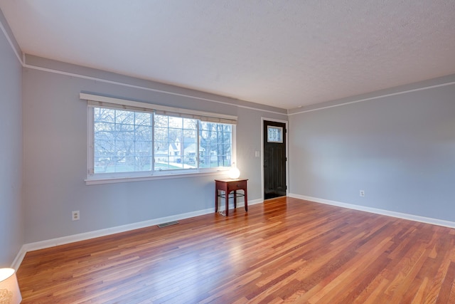 unfurnished room featuring wood-type flooring and a textured ceiling