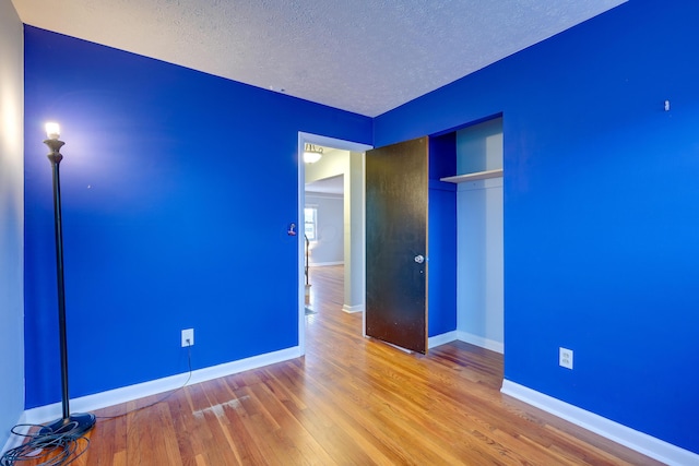 unfurnished bedroom featuring hardwood / wood-style floors, a textured ceiling, and a closet