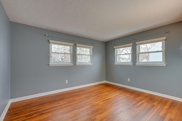 empty room with hardwood / wood-style floors and a textured ceiling