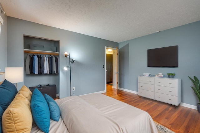 bedroom with hardwood / wood-style floors, a textured ceiling, and a closet