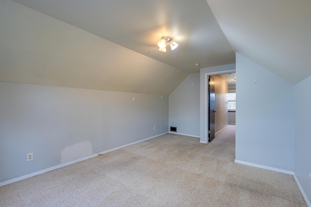 additional living space with light colored carpet and vaulted ceiling