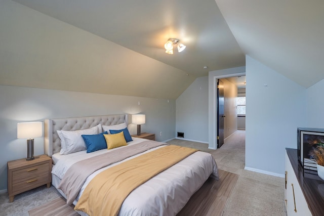 bedroom featuring light colored carpet and lofted ceiling