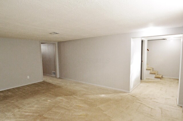 spare room with a textured ceiling and light carpet