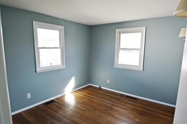 unfurnished room with dark wood-type flooring and a healthy amount of sunlight