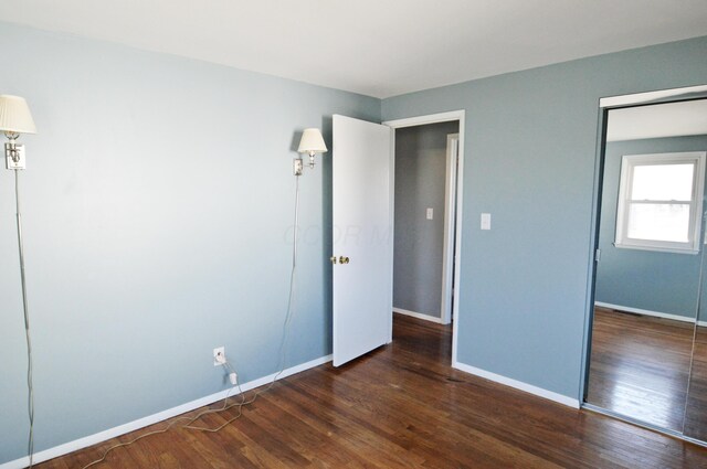 unfurnished bedroom featuring dark hardwood / wood-style flooring and a closet